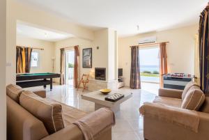 een woonkamer met banken en een pooltafel bij Kalisto Beach Villa in Kato Yialia