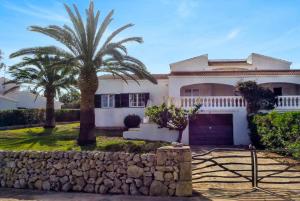 a house with a palm tree and a stone wall at Villa Bini Estrella in Es Canutells