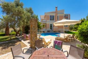 a patio with a table and chairs and a house at Villa Pelagos in Agia Triada