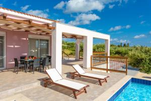 a patio with a table and chairs next to a swimming pool at Vatsa Beach Villa in Kounopetra