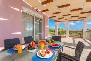 a table with watermelon plates and drinks on a patio at Vatsa Beach Villa in Kounopetra