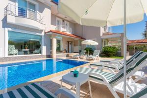 a villa with a swimming pool with chairs and an umbrella at Villa Nirvana in Mugla