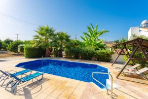 a swimming pool with two chairs and a table at Villa Charoula Pente in Paphos