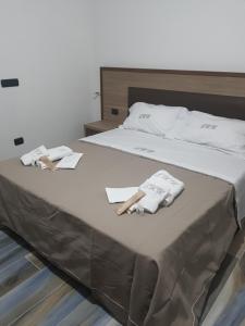 ein Bett mit zwei Handtüchern und zwei Holzschuhen in der Unterkunft LUXURY HOLIDAY HOUSE in Diamante