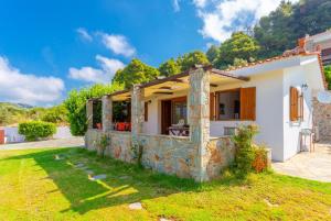 una pequeña casa blanca con una pared de piedra en Villa Katerina, en Panormos Skopelos