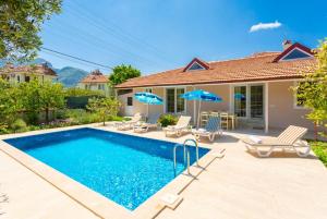 a pool with chairs and umbrellas in front of a house at Villa Duman 3 in Dalyan