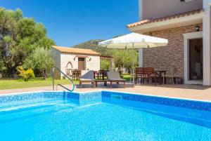 einen Pool mit einem Tisch und einem Sonnenschirm in der Unterkunft Villa Eufrosini in Svoronata