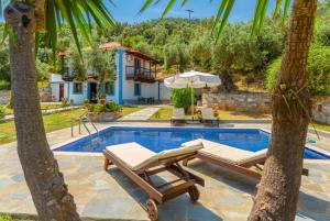 una piscina con 2 tumbonas y una casa en Villa Glysteri, en Panormos Skopelos