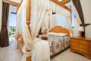 a bedroom with a canopy bed with white curtains at Sun Beach Villa Thio in Polis Chrysochous +22 photos