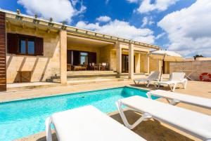 uma piscina com duas cadeiras e uma casa em Water Front Villa Shalom em Binissafuller