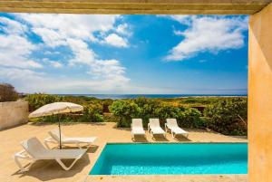 uma piscina com espreguiçadeiras e vista para o oceano em Water Front Villa Shalom em Binissafuller