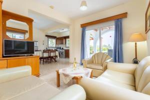 a living room with white furniture and a flat screen tv at Argaka Sun Villa Ena in Argaka