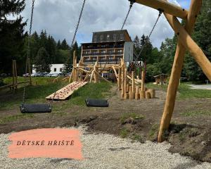 a playground with a wooden swing set in front of a building at Depandance hotelu Kamzík in Malá Morávka
