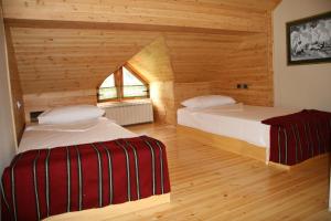 1 dormitorio con 2 camas en una cabaña de madera en Natyral Razma Resort en Razëm