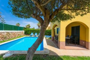 uma piscina com uma árvore ao lado de uma casa em Villa La Luna em Cala en Blanes