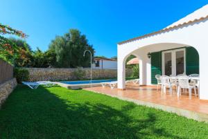 a backyard with a patio with chairs and a pool at Villa Calitja Dos in Cala'n Bosch