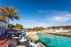 a pool at a resort with tables and chairs at Villa Calitja Dos in Cala'n Bosch