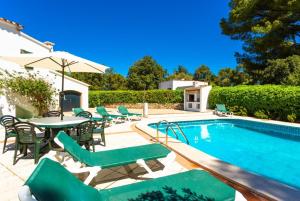 una piscina con sillas verdes, una mesa y una piscina en Villa Luisa, en Cala Galdana