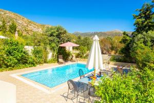 een zwembad met een tafel en een parasol bij Villa Semeli in Kateliós