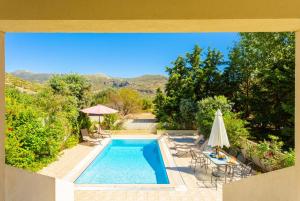 a swimming pool with an umbrella and a table and chairs at Villa Semeli in Katelios