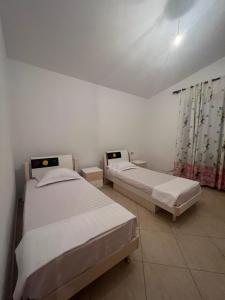 two beds in a room with white walls at Cela House in Divjakë