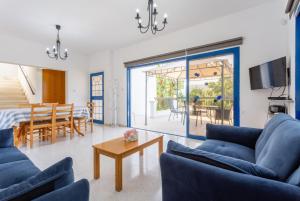 a living room with blue couches and a dining room at Villa Charoula Tria in Paphos City