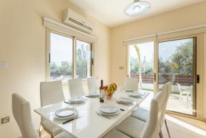 a dining room with a white table and white chairs at Villa Rose in Paphos City