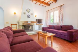 sala de estar con 2 sofás morados y chimenea en Villa Trepuco Dos, en Punta Prima