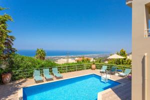 a pool with chairs and the ocean in the background at Villa Ilia in Roussospítion