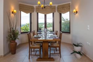 comedor con mesa, sillas y ventanas en Villa Ilia, en Roussospítion