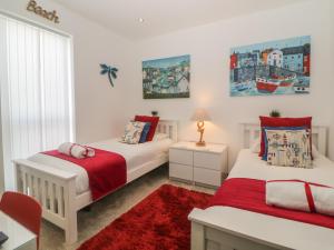 a bedroom with two beds and a red rug at 12 Beachdown in Kingsbridge