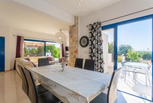 a dining room with a white table and chairs at Villa Charoula Tessera in Polis Chrysochous