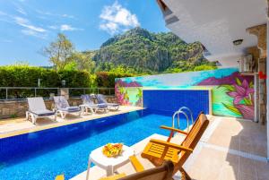 a pool with chairs and a wall with a mural at Villa Asli Paradise in Mugla