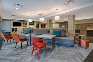 a lobby with a couch and tables and chairs at Home2 Suites East Hanover, NJ in East Hanover