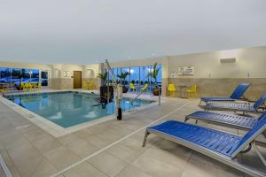 - une piscine avec des chaises et des chaises bleues dans un bâtiment dans l'établissement Home2 Suites East Hanover, NJ, à East Hanover
