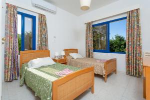 a bedroom with two beds and two windows at Villa Charoula Thio in Polis Chrysochous