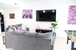 a living room with a couch and a flat screen tv at Insta Worthy Modern Bungalow in Homestead