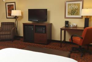 Habitación de hotel con TV, silla y escritorio. en Hampton Inn & Suites Fargo Medical Center, en Fargo