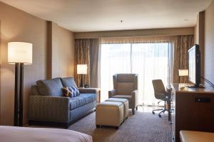フレズノにあるダブルツリー バイ ヒルトン フレズノ コンベンション センターのベッド、ソファ、椅子が備わるホテルルームです。