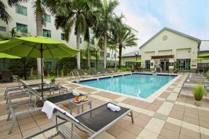 una piscina con sillas y sombrilla en Homewood Suites by Hilton Fort Lauderdale Airport-Cruise Port, en Dania Beach