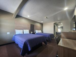 a hotel room with two beds with purple sheets at Scottish Inn and Suites Beaumont in Beaumont