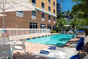 a swimming pool with chairs and an umbrella next to a building at Hampton Inn Hallandale Beach-Aventura in Hollywood