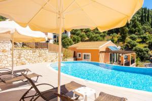 a pool with chairs and an umbrella next to a house at Villa Konstantinos in Katávolos