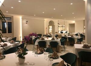 ein Restaurant mit weißen Tischen und grünen Stühlen in der Unterkunft Hotel La Silvana in Selva di Fasano