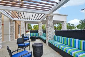Home2 Suites by Hilton Miramar Ft. Lauderdale في ميرامار: فناء به كراسي وطاولات زرقاء وأخضر
