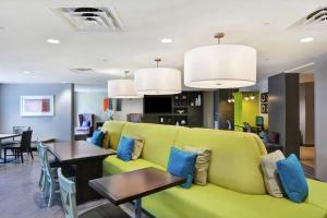a living room with a green couch and a table at Home2 Suites by Hilton Miramar Ft. Lauderdale in Miramar