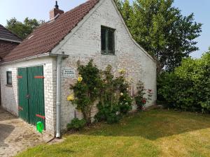 a white brick building with a green door and flowers at Ferienhaus Nordseebrise in Holtgast