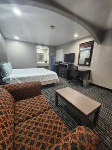 a hotel room with a bed and a couch at Scottish Inn and Suites Beaumont in Beaumont