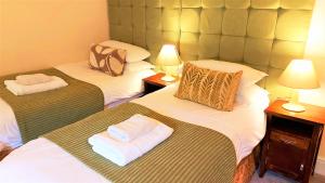 Dos camas en una habitación de hotel con toallas. en Dolgun Uchaf Guesthouse and Cottages in Snowdonia en Dolgellau