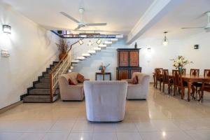 uma sala de estar com uma escada e uma mesa e cadeiras em Spacious 4BR 4BA Family Villa wt Balcony & Lavish Garden em Ratmalana